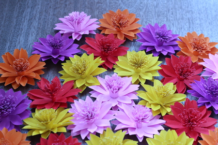 Many colorful paper flowers on a background with a smooth surfaceの写真素材