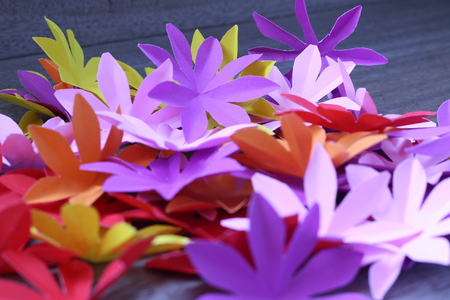 Many colorful paper flowers on a background with a smooth surfaceの写真素材