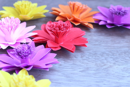 Many colorful paper flowers on a background with a smooth surfaceの写真素材