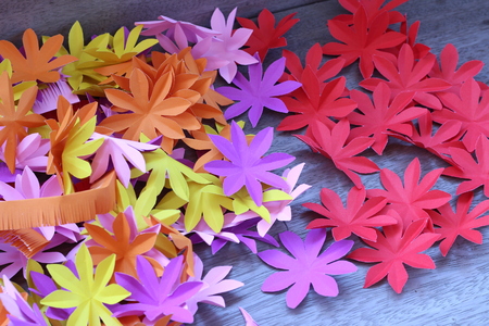 Many colorful paper flowers on a background with a smooth surfaceの写真素材