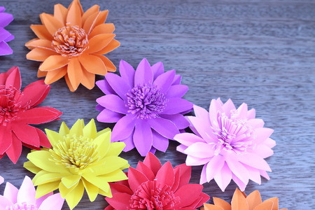 Many colorful paper flowers on a background with a smooth surfaceの写真素材