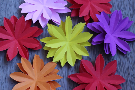 Many colorful paper flowers on a background with a smooth surfaceの写真素材