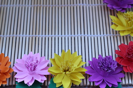 Many colorful paper flowers on a background with a smooth surfaceの写真素材