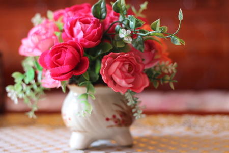 The beautiful rose is arranged in a vase, placed on the tableの写真素材