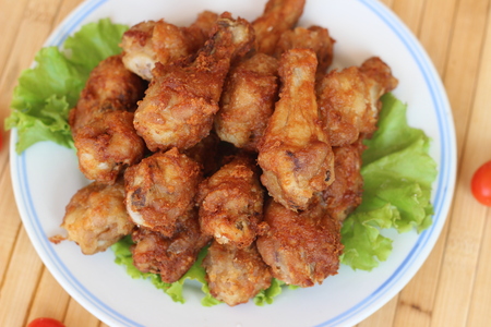 Deep fried chicken is served in a flat white dish on a brown backgroundの写真素材