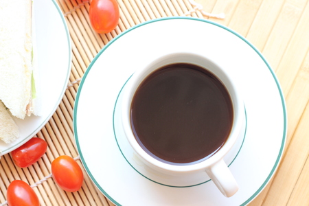 Black coffee and sandwich lay on a brown backgroundの写真素材