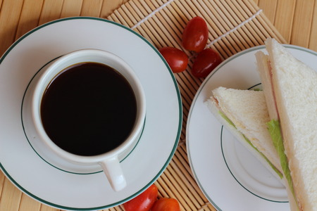 Black coffee and sandwich lay on a brown backgroundの写真素材