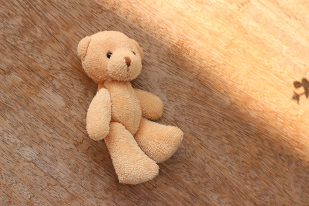 Cute brown bear doll on brown backgroundの写真素材