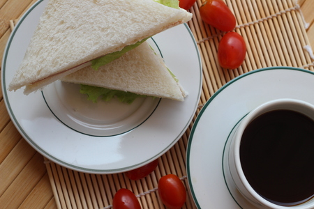 Black coffee and sandwich lay on a brown backgroundの写真素材