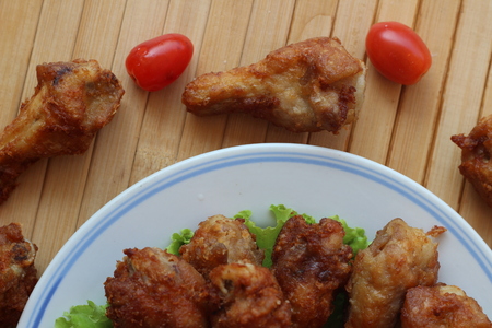 Deep fried chicken is served in a flat white dish on a brown backgroundの写真素材