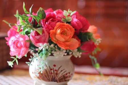 The beautiful rose is arranged in a vase, placed on the tableの写真素材