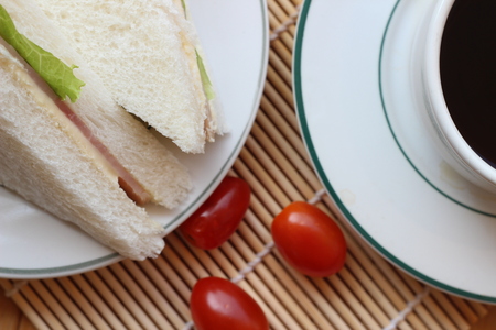 Black coffee and sandwich lay on a brown backgroundの写真素材