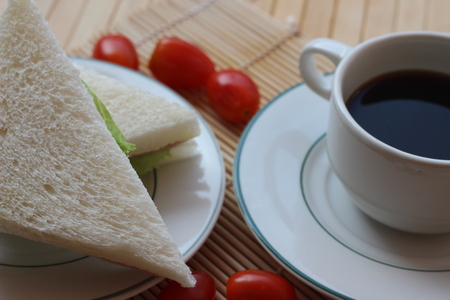 Black coffee and sandwich lay on a brown backgroundの写真素材