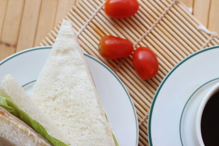 Black coffee and sandwich lay on a brown backgroundの写真素材