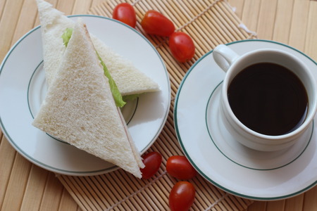 Black coffee and sandwich lay on a brown backgroundの写真素材