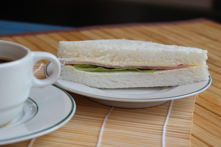 Black coffee and sandwich lay on a brown backgroundの写真素材