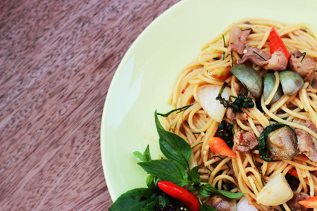 Stir spa-style spaghetti with Thai style meat in a green dish on a brown backgroundの写真素材
