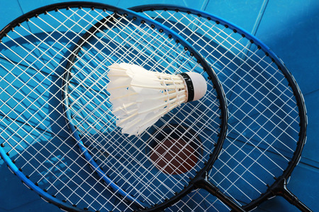 Badminton rackets and badminton balls are placed on a brown background