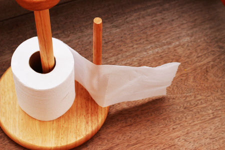 Wooden toilet paper holder placed on a brown background.の写真素材
