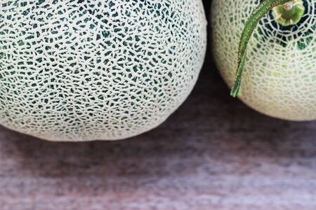 Melon fruit is spherical, has a rough texture and delicious sweet taste is cut on  brown background.の写真素材