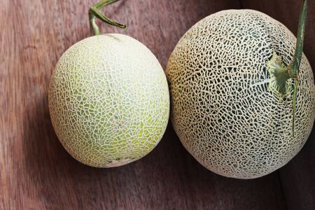 Melon fruit is spherical, has a rough texture and delicious sweet taste is cut on  brown background.の写真素材
