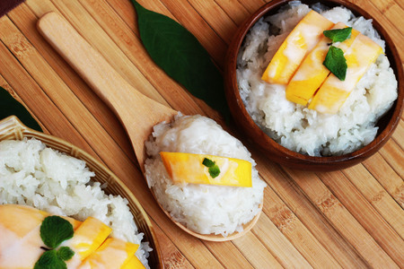 Mango sticky rice is put in a wooden container placed on a brown wooden tableの写真素材