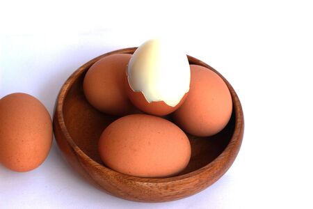 Boiled eggs that are not peeled and peeled in a brown container on a white background.の写真素材