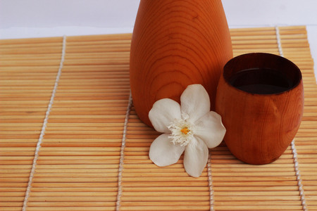 SAKE liqueur in a brown wooden bottle on a light brown background.の写真素材