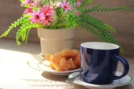 On the brown wooden table there is a blue coffee mug inside, with black coffee and golden fish in the morning.の写真素材