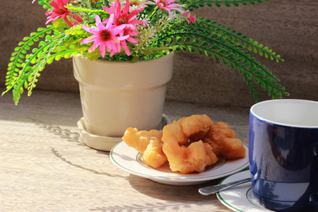 On the brown wooden table there is a blue coffee mug inside, with black coffee and golden fish in the morning.の写真素材