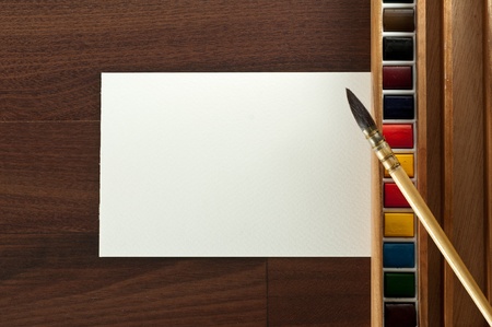 Vintage watercolor paint with  brush and blank paper on brown tabel. Top view.の写真素材