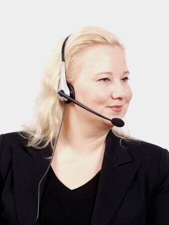 Woman at a helpdesk with headset, dressed in a business suit, smiling while looking to the rightの写真素材