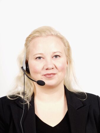 Woman at a helpdesk with headset, dressed in a business suit, smiling while looking at the cameraの写真素材
