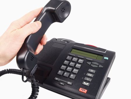 Someone lifting the handset off from the office phone, isolated on white backgroundの写真素材
