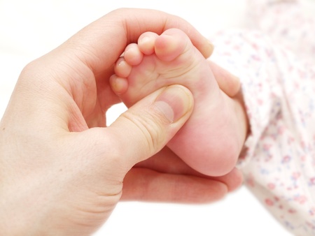 A baby receiving foot massage, towards white backgroundの写真素材
