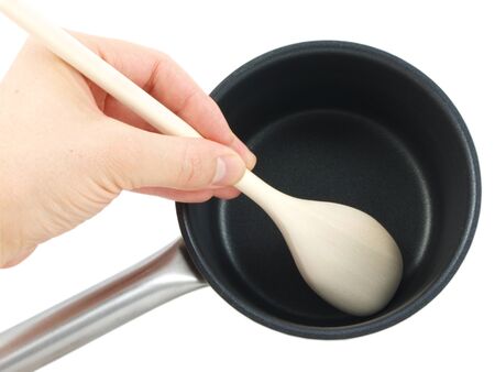 Stainless steel kettle, with wooden spatula and human hand, isolated towards white backgroundの写真素材