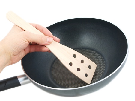 Frying pan with wooden spatula, isolated with human hand towards white backgroundの写真素材