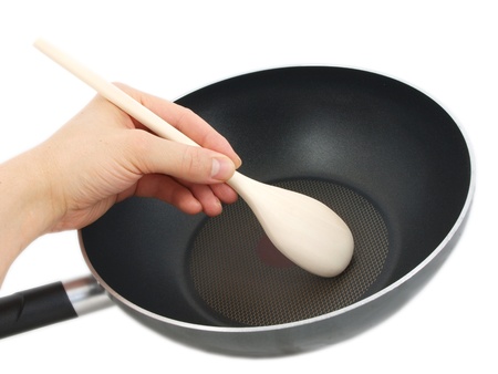 Frying pan with wooden spatula, isolated with human hand towards white backgroundの写真素材
