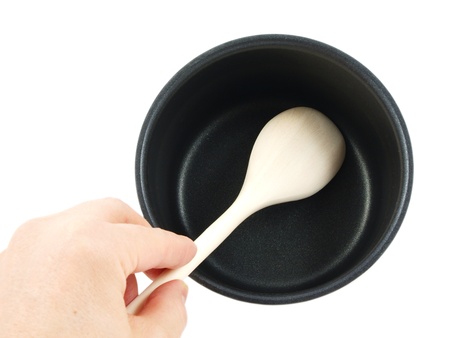 Stainless steel kettle, with wooden spatula and human hand, isolated towards white backgroundの写真素材