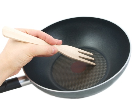 Frying pan with wooden spatula, isolated with human hand towards white backgroundの写真素材
