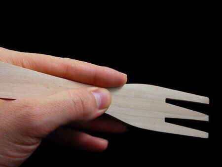 Person holding a wooden spatula, isolated towards black backgroundの写真素材