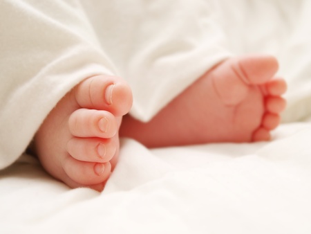 Baby feet covered in white sheet, isolated in whiteの写真素材