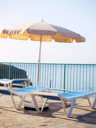 Sunbeds and parasol on deck, at summer