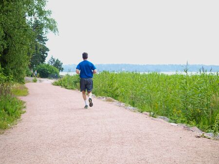 Person running alone on gravel road, at summerの写真素材