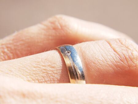 White and yellow gold ring, with a diamond, on male fingerの写真素材