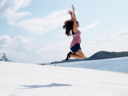 Young brunette female, jumping of joy on roof topの写真素材