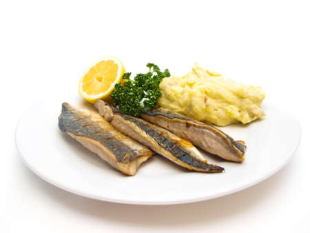Fried mackerel on white plate with half lemon, green parsley and mashed potatoesの写真素材