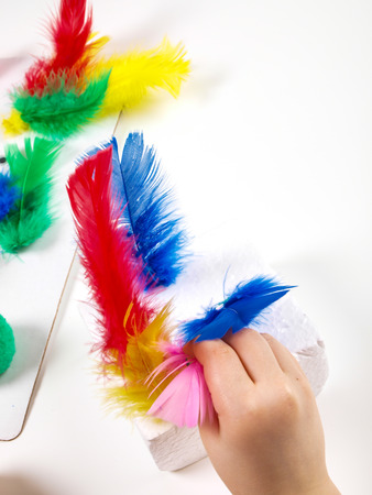 Little girls hands playing with colorful feathers, creating Easter decorationの写真素材