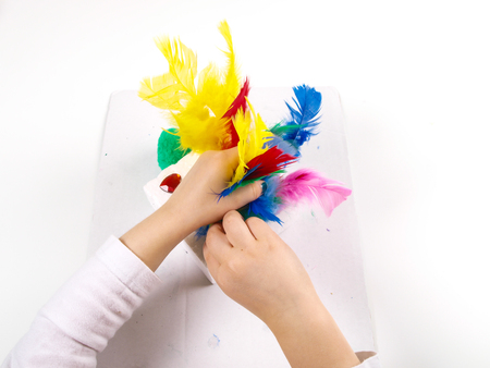 Little girls hands playing with colorful feathers, creating Easter decorationの写真素材