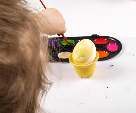 Little girls hands playing with colorful paint, creating Easter decorationの写真素材